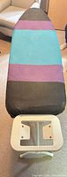 Top view of ironing board showing striped cover and iron rest