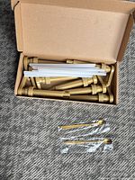 box with eight gold pumps, clear tubes, and two wrapped gold spoons