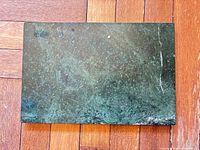 Dark-green marble board front view on wood floor