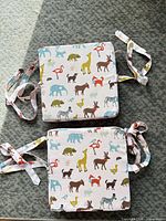 Top view of two pink animal print square seat cushions with attached tie straps