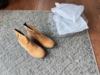 Top view of tan faux suede ankle boots with packing inserts beside them