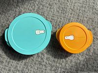 Teal and orange bowls with lids closed showing top view and vent toggles
