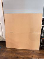 Front view of flat-packed corrugated boxes leaning against wall