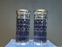Front view of both shakers with lids on showing pierced sleeve pattern