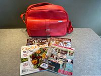 Front view of red Samsonite shoulder bag with four magazines in front