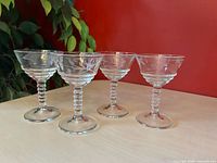 Four etched coupe glasses on tabletop
