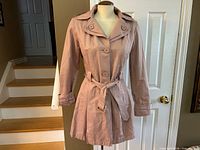 Front view of blush pink trench coat on mannequin with belt tied