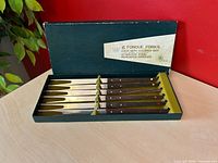 Open box showing six fondue forks in fitted slots