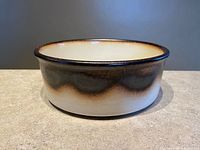 Side view of porcelain bowl showing brown drip glaze and cream body