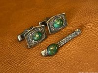 Cufflinks and tie pin grouped on leather surface