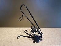 Side view of black wrought iron wine holder showing grape leaf accents and scroll feet
