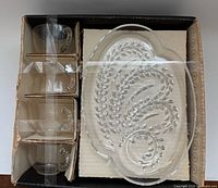 Box opened showing four cups in cardboard slots and one plate on right