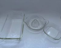 Pyrex rectangular dish, glass citrus reamer and additional glassware in frame