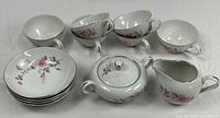 All pieces arranged: six cups, four bowls, stacked bowls/plates, sugar bowl with lid, creamer