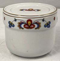 Side view of jar with lid on displaying motif