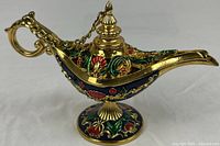 Full view of gold-tone enamel Aladdin lamp trinket box on pedestal base