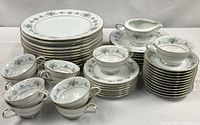 Full lot showing stacked plates, cups, saucers and cream pitcher