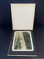 Album opened showing mounted colour-tinted landscape photograph