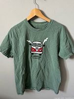 Full view of green Cannibus graphic T-shirt on hanger