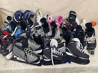 Group shot of approximately 15 pairs of children’s ice hockey skates on surface