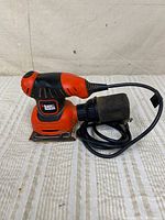 Full view of Black & Decker QS540 palm sander with cord and dust bag attached