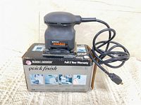Sander atop original box showing full item and cord