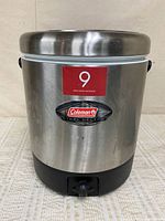 Front view of Coleman stainless steel beverage dispenser with lid