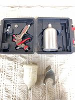 open case showing spray gun, metal cup, plastic cup, hanger