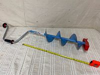 Full view of disassembled two-piece auger with tape measure for scale