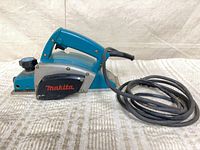 Left side view showing Makita branding, front depth knob and power cord