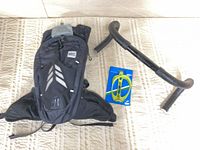 Backpack, handlebar, and packaged water bottle cage laid out