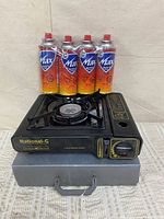 Stove on case with four butane cans behind