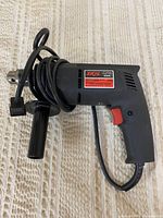 Full view of Skil corded drill with side handle and cord