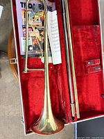 Trombone disassembled in red-lined case with slide, bell, bracing and sheet music visible
