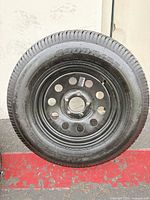 Full view of tire mounted on black steel rim showing overall condition