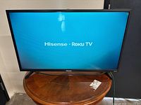 Front view of Hisense Roku TV powered on showing startup logo