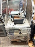 Full view of ProtoMat C100 HF machine inside enclosure on wheeled stand