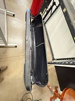 Side view of open black rooftop cargo box showing interior and mounting rails