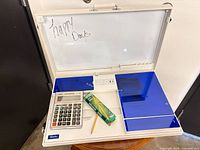 Worky workstation open showing whiteboard lid, outlets, USB ports, blue panels, calculator, pencil box, pencil