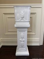Front view of pedestal with planter on top showing overall form and relief design