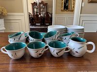 Cups, creamer, two stacks of plates/bowls on tabletop