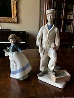 Full view of both porcelain figurines: young girl and bricklayer