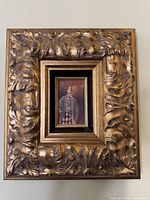 full view of ornate gold frame with painting centered