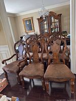 Front view of all eight chairs showing armchair arms, carving detail, and upholstery