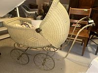 Full view of wicker baby carriage showing body, hood, wheels and handle