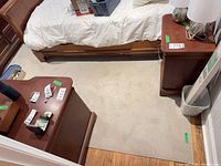 Rug section between two nightstands showing beige low pile surface and central stain