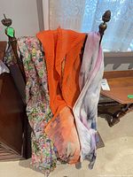Three scarves on chair: floral, orange pleated, pastel abstract