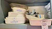 Nested CorningWare dishes, glass lid, measuring sets in cabinet