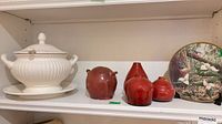Shelf view showing soup tureen set, four red vases and decorative plate