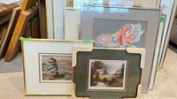 Group of five framed artworks leaning against wall
